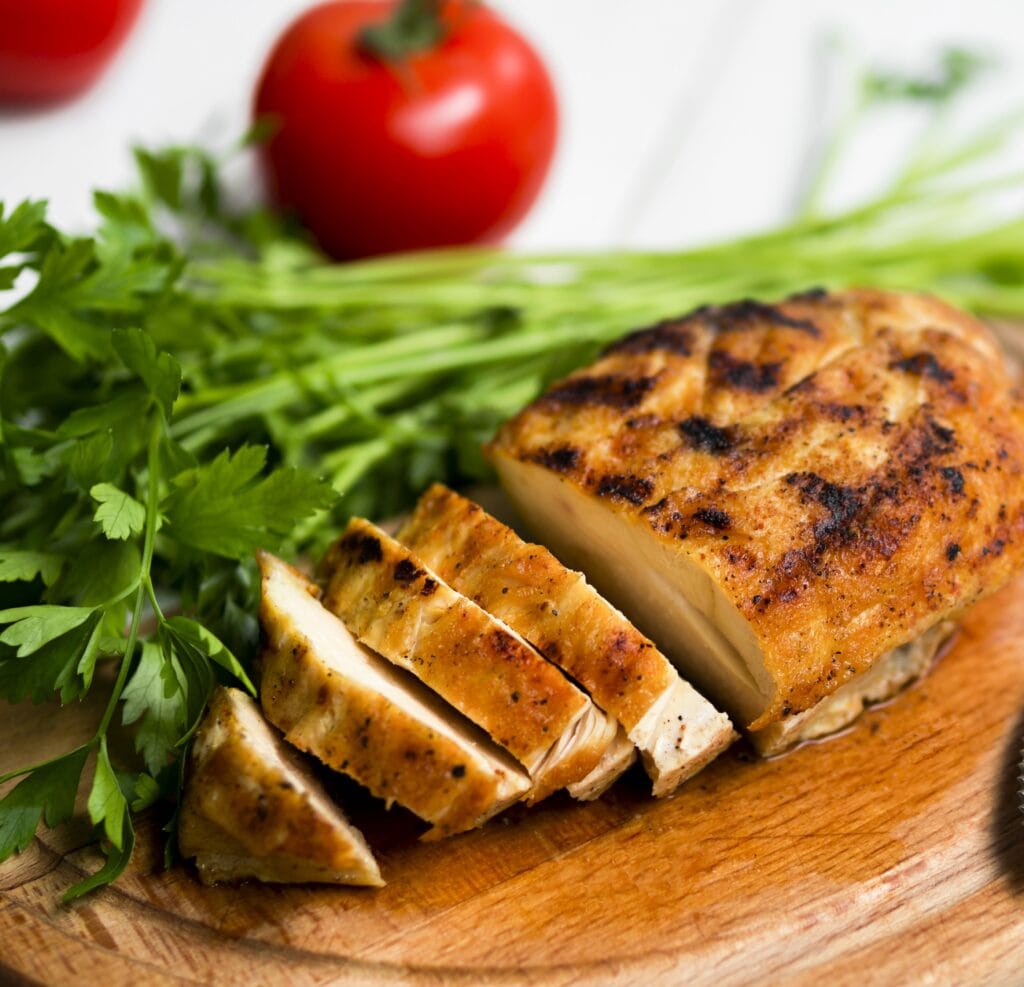 Thinly sliced chicken breasts baked to golden perfection, garnished with fresh parsley and served on a wooden cutting board.