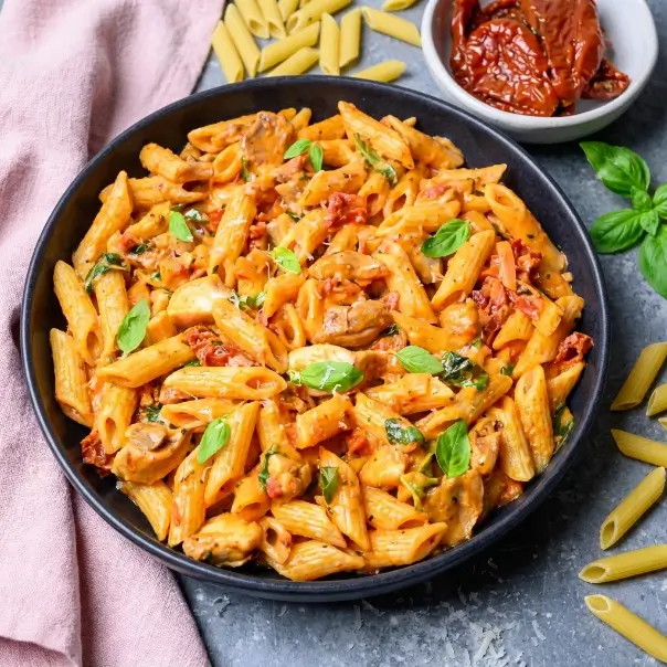 Creamy Tuscan chicken pasta ingredients with chicken, penne, sun-dried tomatoes, spinach and Parmesan
